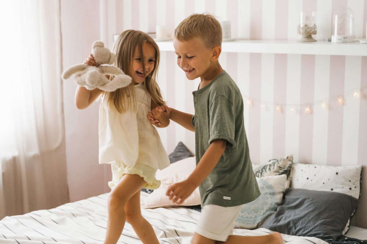 A girl and boy dancing on bed